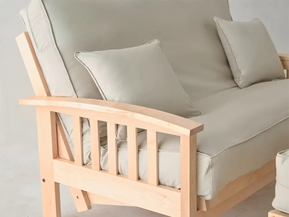 A light wood futon with beige cushions and two matching throw pillows, shown against a plain background.