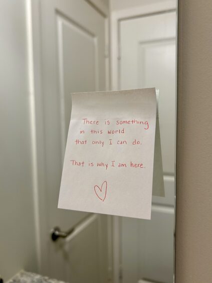 A handwritten note on a bathroom mirror reads, "There is something in this world that only I can do. That is why I am here," followed by a heart symbol.