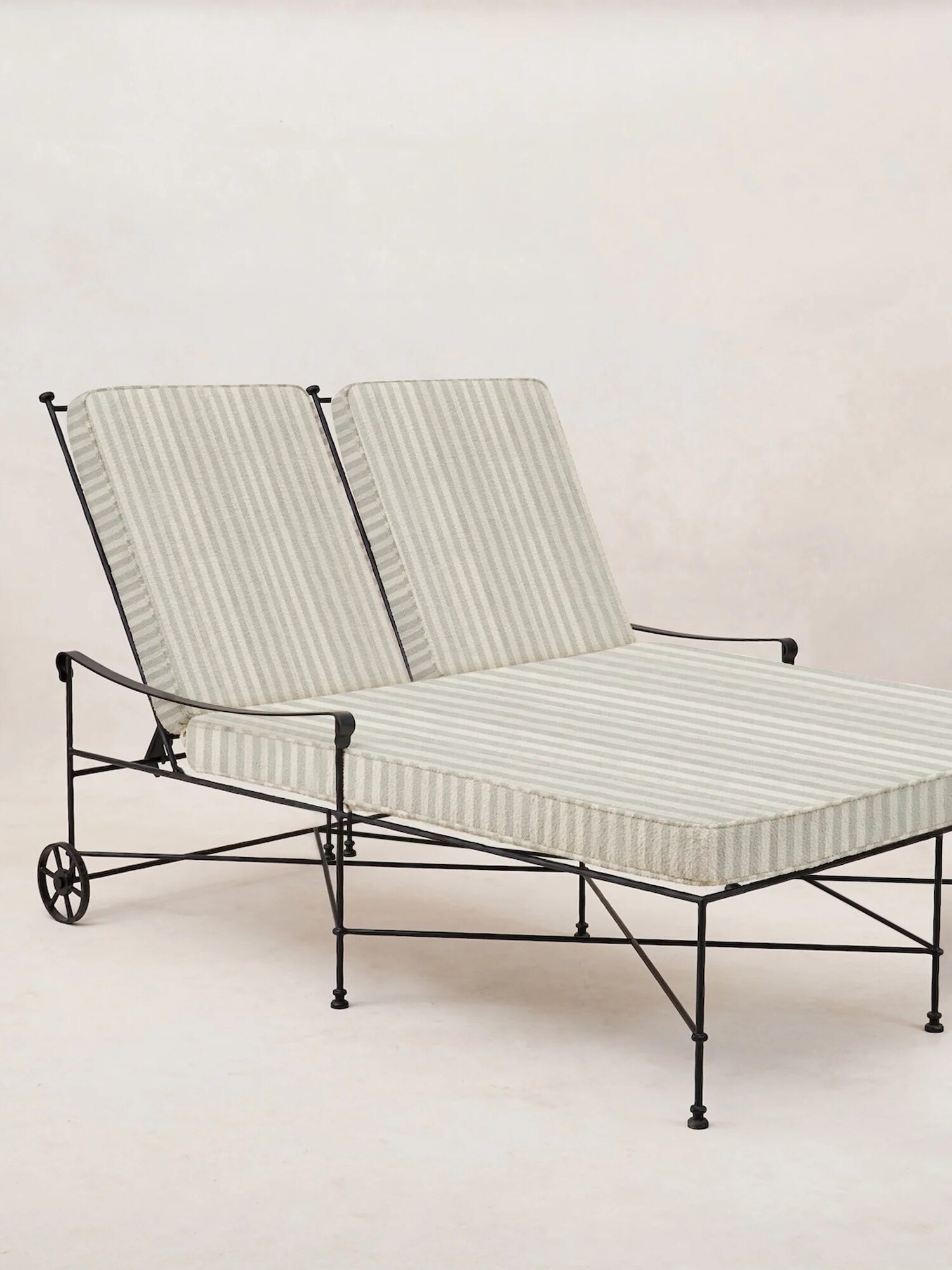 A double outdoor lounge chair with a black metal frame and two adjustable striped cushions, set against a plain light background.
